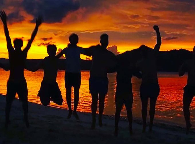 Travellers on the beach at sunset during a Palawan expedition